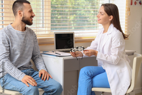 Eye exam and vision care, optometrist consulting with male patient using tria...