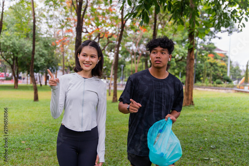 Quadro su tela Asian sporty man and woman pick up trash together in public park