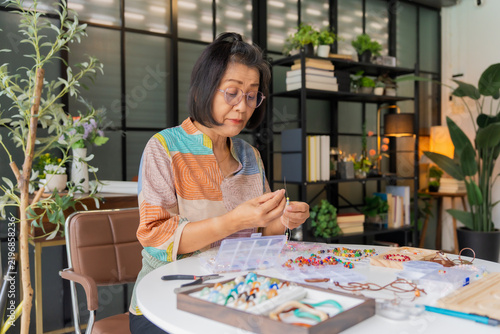 Mature Asian woman making necklace handcrafted