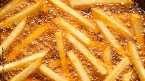Delicious french fries frying in hot boiling oil in a deep fryer pot close up view fast food snack