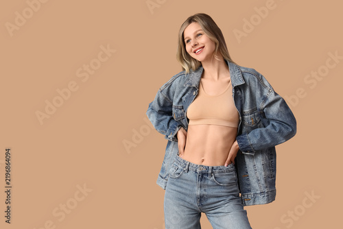 Young happy woman in stylish blue jeans posing on beige background