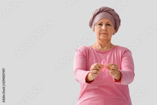 Senior woman after chemotherapy with pink ribbon on white background. Breast ...