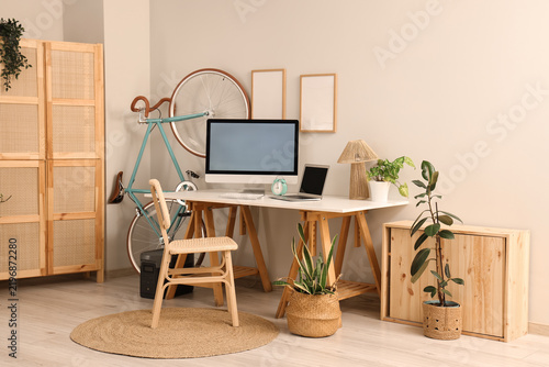 Interior of home office with workplace, bicycle and folding screen