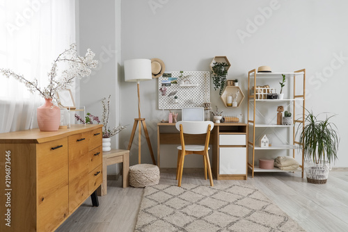 Interior of light office with workplace, pegboard and shelves