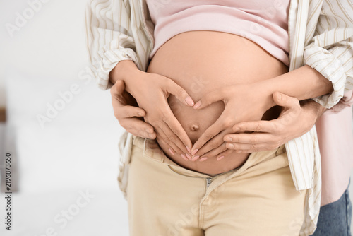 Happy pregnant couple hugging in bedroom, closeup
