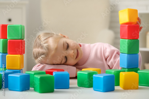 Cute little girl with plastic cubes at table in childrens room, closeup
