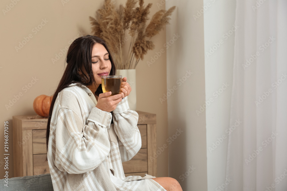 Obraz premium Young woman drinking green tea on autumn day at home