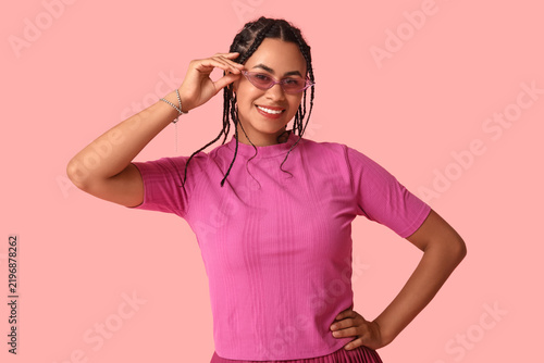 Beautiful young African-American woman with dreadlocks on pink background