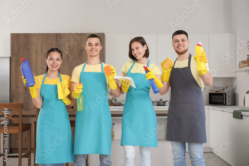 Group of young janitors with cleaning supplies in kitchen