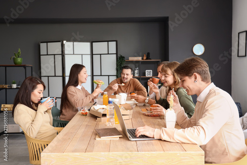 Business colleagues having lunch at table in office kitchen