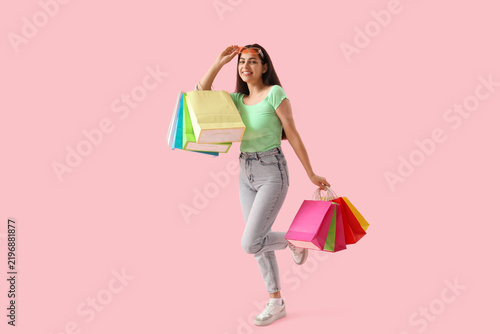 Beautiful young happy woman with shopping bags on pink background. Summer sal...