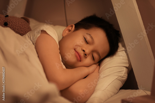Cute little Asian boy sleeping in bed, closeup