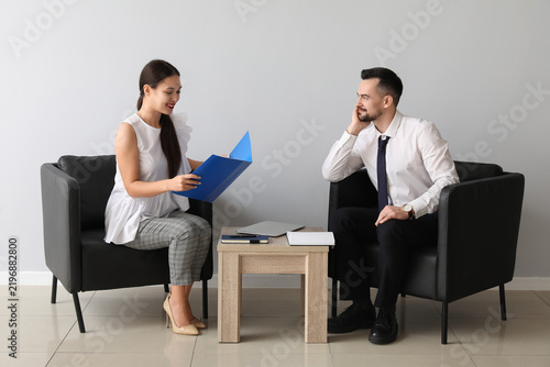 Human resources manager interviewing applicant near light wall in office