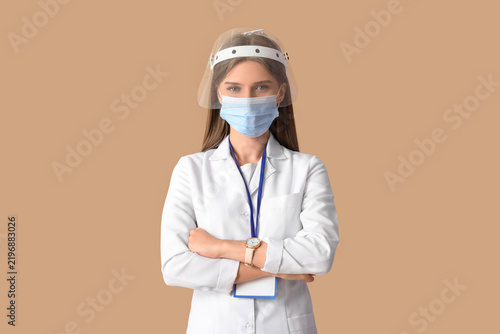 Female doctor in protective masks on beige background