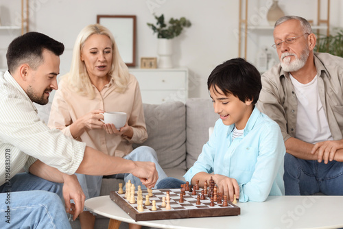 Little boy playing chess with his father at home