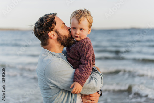 Father and son hugging and kissing next to sea