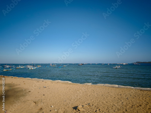 Konstfotografi Sandy beach with traditional outrigger boats floating on calm tropical ocean und