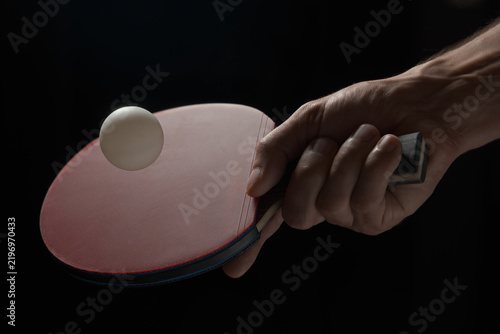 Close-up of a hand holding a table tennis racket and ball
