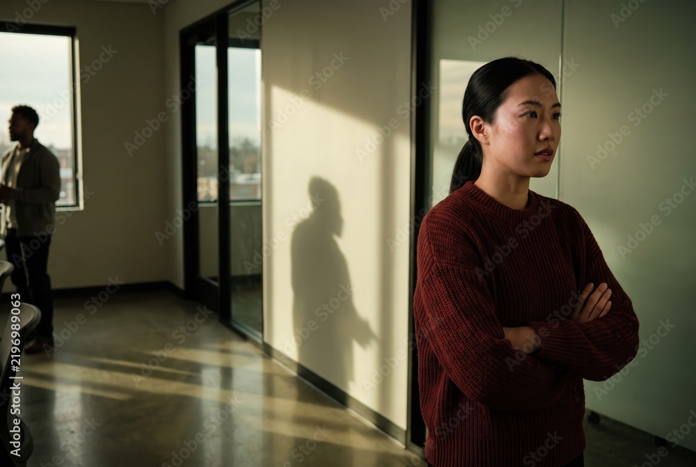Fototapeta premium Generative AI, Serious Asian woman standing with crossed arms in office setting