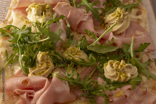 Фотография Thinly sliced ham with arugula and herb aioli dollops , warm cafe lighting, delicate meat folds, peppery greens, artisanal food