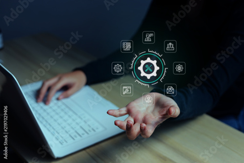Woman Showing Holographic IT Service Icon while Typing on Laptop