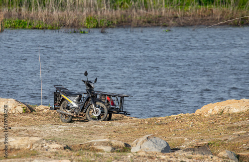Foto Traditional local motorcycle with a sidecar parked on a rocky riverbank