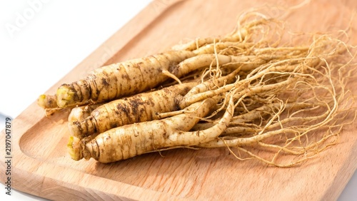 Fresh ginseng roots on wooden cutting board