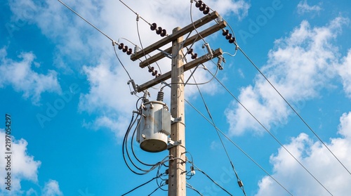 Concrete utility pole with step down transformer and electrical power line cables, representing energy infrastructure, electricity distribution grid and modern public utility engineering.