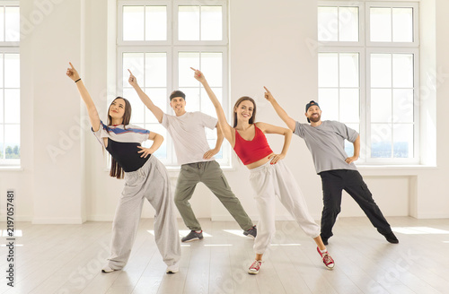 Dancers perform coordinated group dance in studio. Four adults strike coordinated poses in a room, expressing friendship, rhythm and confidence. A vibrant concept of shared creative energy.