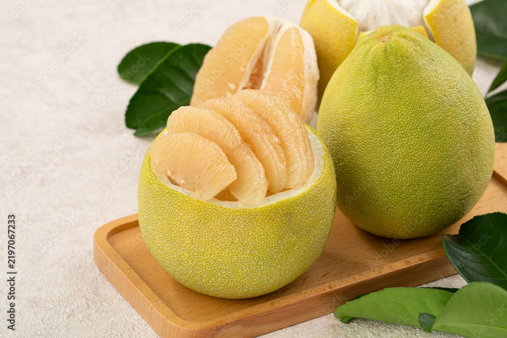 Naklejka premium Fresh pomelo fruit with leaf on white table background.