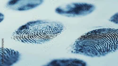 A close up view shows various fingerprint patterns printed on paper for analysis in a forensic lab environment