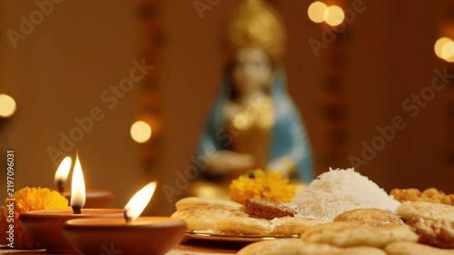 Kojagari Lakshmi Puja, decorated thali with coins, rice, and diya, blurred backdrop of Lakshmi idol