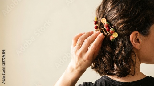 Woman wearing a colorful fruit hairpin in her dark curly hair