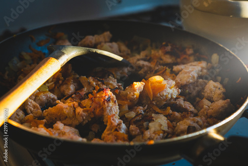Canvastavla A close-up shot of freshly cooked minced meat with onions and carrots being stirred in a frying pan on a gas stove in the kitchen