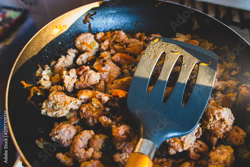 Konstfotografi A close-up shot of freshly cooked minced meat with onions and carrots being stirred in a frying pan on a gas stove in the kitchen