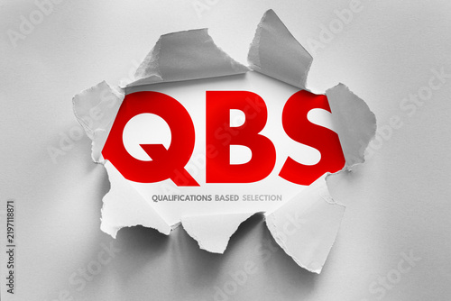 QBS stands for qualifications based selection. Text shown under a torn paper surface. Selection process concept for engineering, architectural, or professional services based on expertise