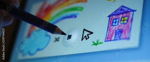 Close up of stylus drawing colorful house and rainbow on digital tablet screen.