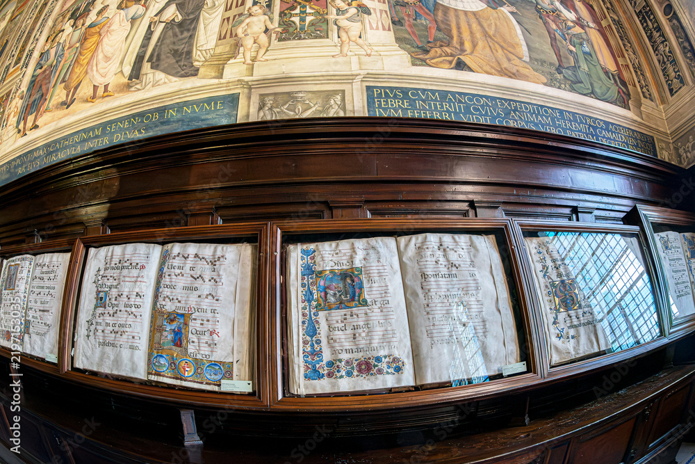 Obraz premium Antique choir books displayed in wooden cabinets in the famous Piccolomini Library, inside the Siena Cathedral (Duomo di Siena) in Tuscany, Italy. Built in the late 15th century (starting in 1492).
