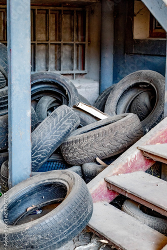 Картината върху платно High angle view of a pile of old used car tires stacked next to a rustic wooden