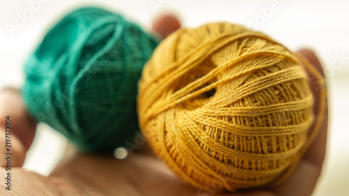 Hand Holding Yellow and Green Embroidery Thread Balls