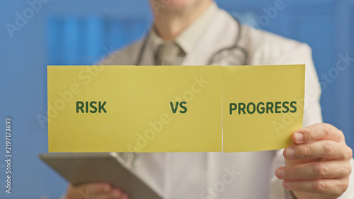 Doctor holding yellow paper labeled risk vs progress, highlighting the ethical dilemma of integrating ai into medicine and balancing innovation, patient safety, and future healthcare decisions
