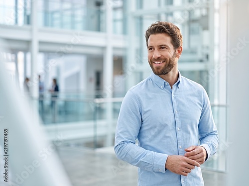 Successful Young Businessman Smiling in a Bright Modern Office Environment