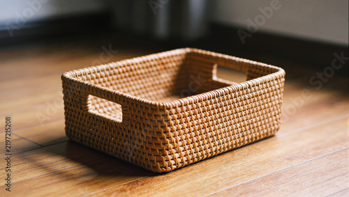 Empty woven basket with handles on wooden table, natural fiber storage basket with copy space