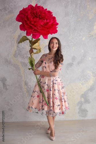 Fotografie Happy young woman and girl in floral dress holding a giant artificial peony flow