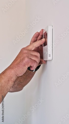 Senior man adjusting a smart home thermostat