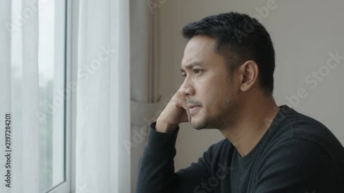 Young Man Feeling Stressed and Overwhelmed Near a Window at Home