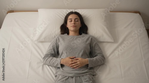 Young woman Relaxing in Bed and Taking a Deep Breath for Rest, Stress Relief and Mental Wellbeing
