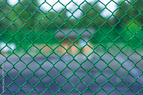 Fotografie Green chain link fence texture close up with blurred sports ground in background