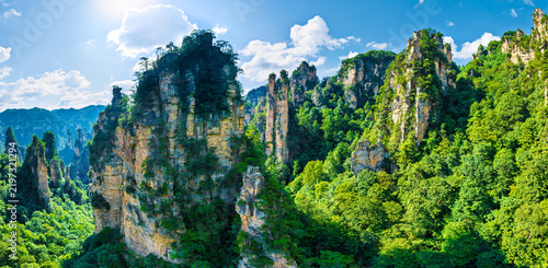 Cuadro en lienzo Tall sandstone karst pillars rise above a lush green forest canopy under bright blue skies in scenic Zhangjiajie National Forest Park
