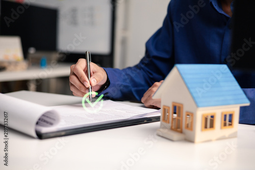 Obraz na płótnie Professional reviews and signs a mortgage document beside a house model